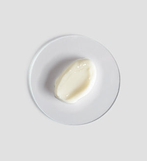 Close-up of a smooth, creamy white skincare product texture displayed on a clear round surface, representing Renight Cream | [ comfort zone ] for body care and wellness.