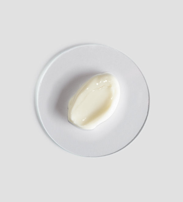 Close-up of a smooth, creamy white skincare product texture displayed on a clear round surface, representing Renight Cream | [ comfort zone ] for body care and wellness.