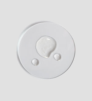 Clear liquid droplets on a white surface showcasing the texture of Tranquillity Oil (Bath & Body) | [ comfort zone ] for skincare and body care wellness.