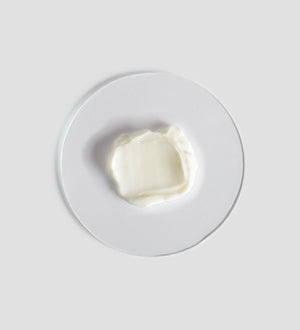 A smooth dollop of creamy white Tranquillity Body Cream | [ comfort zone ] displayed on a clear round surface, highlighting its rich texture for skincare and body care.