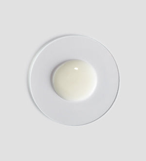 Sample of creamy white Tranquillity Shower Cream | [ comfort zone ] on a clear round dish against a light gray background, highlighting its smooth texture for skincare and body care.