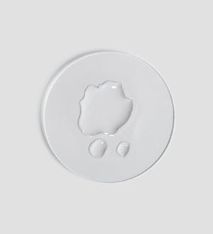 Clear liquid drops on a white surface demonstrating the texture of Remedy Toner | [ comfort zone ], highlighting its lightweight and hydrating skincare formula.