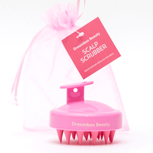 Pink scalp scrubber with soft silicone bristles and ergonomic handle, packaged with a sheer pink drawstring bag for gentle exfoliation and detangling, Scalp Scrubber [Revitalizing Scalp Massager] | Dreambox Beauty.