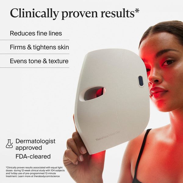 Woman holding TheraFace Mask Glo | Therabody with red light therapy on her face, promoting skincare benefits like reducing fine lines, firming skin, and evening tone.