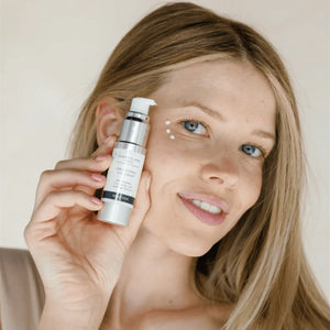 Woman applying Enlightened Eye Cream | DermaplanePro to under-eye area, demonstrating gentle skincare routine for refreshed and hydrated skin.