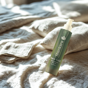 Muscle Relief Oil | Shankara bottle with pump dispenser resting on soft textured linens in warm natural light, highlighting skincare and body care wellness.