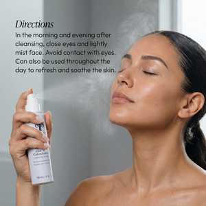 Woman with eyes closed spraying a fine mist on her face from a bottle of Aloe & Calendula Calming Mist | Circadia skincare product, demonstrating calming and refreshing use.