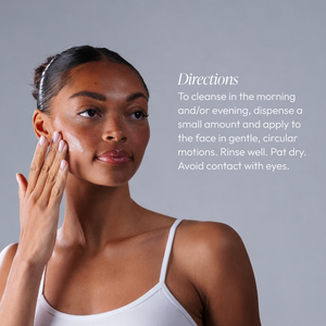 Woman gently applying Amandola Milk Cleanser | Circadia to her cheek, demonstrating a skincare routine with directions visible on a gray background.