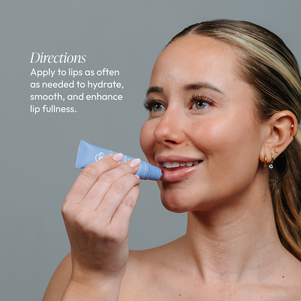 A woman smiling while applying Lip Renewing Hydrator - Watermelon | Circadia to her lips, demonstrating a skincare routine for hydration and lip enhancement.