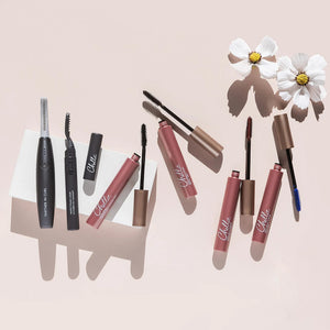 Deluxe Heated Eyelash Curler | Chella displayed alongside mascara tubes and applicators on a light background with white flowers, highlighting beauty and wellness tools.