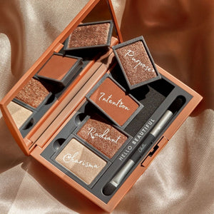 Open Manifest Bronze Eyeshadow Palette | Chella featuring five warm bronze and copper shades with names like Purpose, Intention, Radiant, and Charisma, displayed with a dual-ended brush on a satin fabric background.