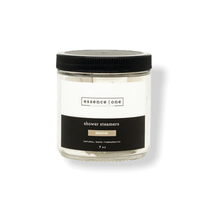 Clear glass jar with black lid containing shower steamers labeled "essence one" and "Breathe," part of the Shower Steamer | Essence One collection for wellness and body care.