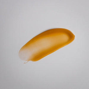 Close-up of a smooth amber gel swatch on a light surface representing the texture of Tightening Eye Gel | Alchimie Forever skincare product.