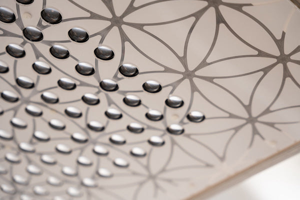 Close-up detail of a metallic surface with polished rounded nodes arranged in a geometric floral pattern, showcasing craftsmanship of the Ammortal Chamber | Ammortal wellness device.