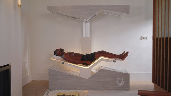 A man relaxing on a modern wellness device designed for body care and recovery, featured as Ammortal Chamber | Ammortal in a serene spa-like setting.