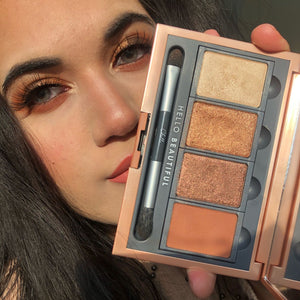 Close-up of a woman holding the Manifest Bronze Eyeshadow Palette | Chella, showcasing warm bronze and gold shades applied on her eyelids with a double-ended applicator inside the palette.