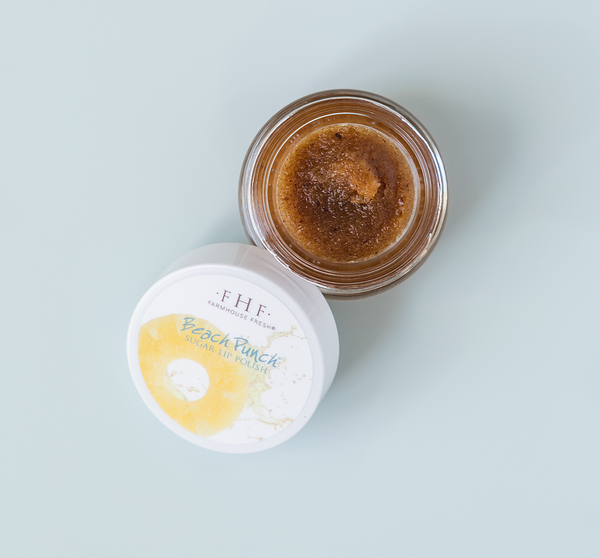 Open jar of Beach Punch® Lip Polish | Farmhouse Fresh showing textured brown sugar polish inside with white lid featuring yellow citrus design on a light background.