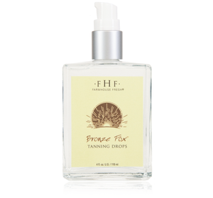 Clear glass pump bottle of Bronze Fox® Tanning Drops | Farmhouse Fresh with a light yellow label and sunburst design, skincare product for a natural tan.
