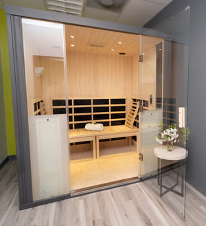 Modern wooden sauna interior with bench seating, towel, and glass door, designed for wellness and relaxation featuring HaloSauna™ | Halotherapy Solutions.
