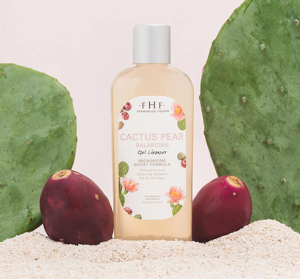 Cactus Pear Balancing Gel Cleanser | Farmhouse Fresh bottle displayed on sand with cactus pads and prickly pear fruits, showcasing skincare product in natural setting.