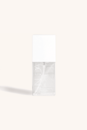 Clear spray bottle with white cap labeled Face Tan Water - Dark | NUDA, showcasing skincare product against light neutral background for body care and wellness.