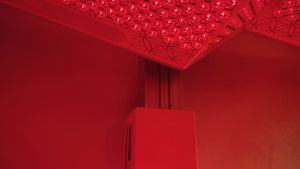 A close-up view of the red-lit interior corner of the Ammortal Chamber | Ammortal wellness device featuring an illuminated panel with circular elements designed for recovery and body care.