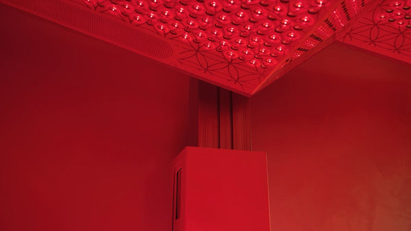 A close-up view of the red-lit interior corner of the Ammortal Chamber | Ammortal wellness device featuring an illuminated panel with circular elements designed for recovery and body care.