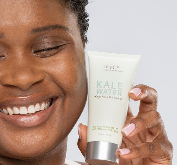 Smiling person holding a tube of Kale Water Weightless Moisturizer | Farmhouse Fresh, showcasing skincare product for lightweight, oil-free hydration with a fresh matte finish.