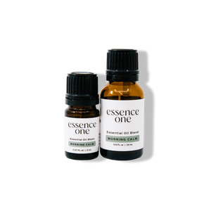 Two amber glass bottles with black caps labeled "essence one" Essential Oil Blends | Essence One, featuring the Morning Calm scent in 5ml and 15ml sizes for wellness and body care.