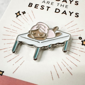 Fab Spa Life Enamel Pin - Limited Edition | Lucky Owl featuring a relaxing figure lying face down on a massage table with a towel wrapped on their head, symbolizing wellness and self-care.