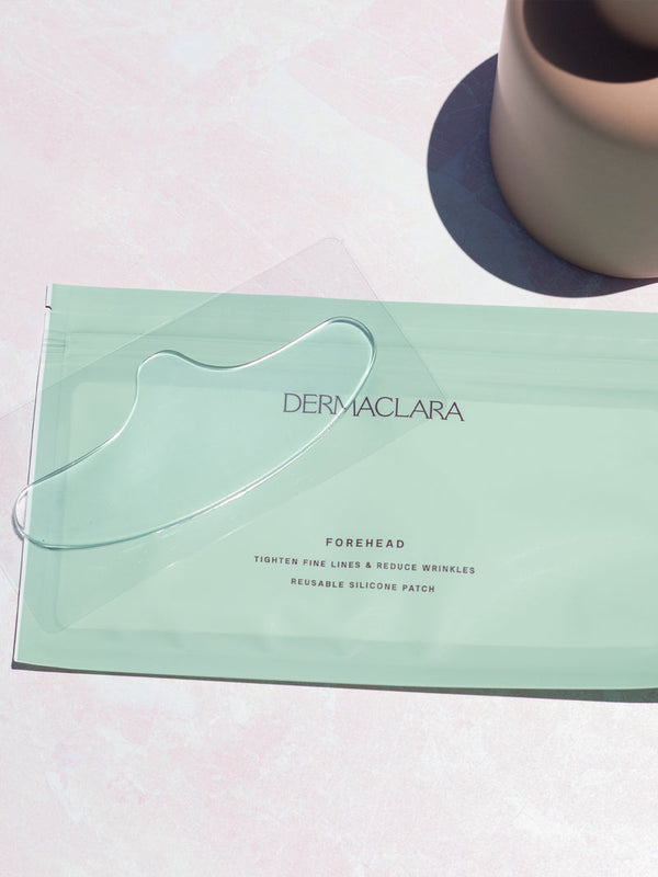 Clear reusable silicone patch designed to smooth forehead fine lines and wrinkles, displayed on pastel green Dermaclara packaging for SiliconeFusion™ Forehead Patch | Dermaclara.