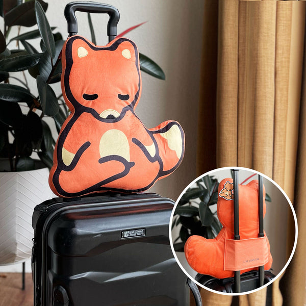 Meditating Fox Plushie | Lucky Owl soft orange plush shaped like a calm meditating fox sitting on a black suitcase handle, ideal for travel comfort and wellness support.