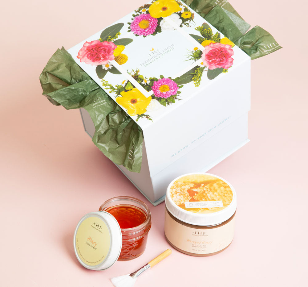 Gift set packaging with floral design featuring two skincare jars and an applicator brush for the Honey I’m Smooth Limited Edition Set | Farmhouse Fresh.