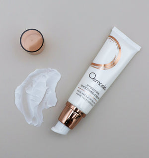 Tube of Hydrafirm Smoothing Cream | Osmosis skincare product with white cream and open cap on a neutral surface, highlighting its smooth texture and packaging design.
