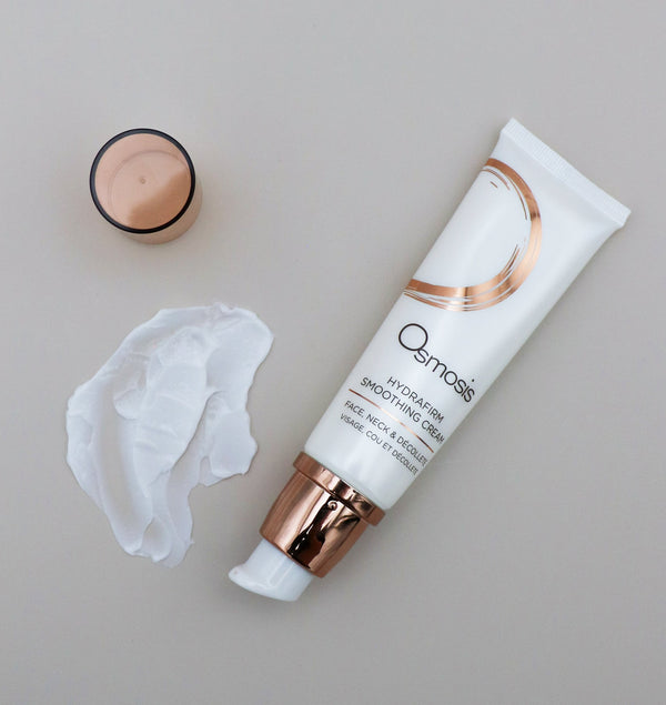 Tube of Hydrafirm Smoothing Cream | Osmosis skincare product with white cream and open cap on a neutral surface, highlighting its smooth texture and packaging design.