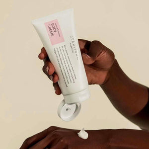 A person applying Jasmine Tuberose BODY CRÈME | Sparitual from a white tube onto their hand, highlighting skincare and body care wellness.