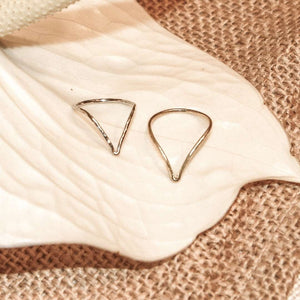 Two delicate silver rings with geometric designs resting on a white textured ceramic leaf dish, showcasing the Journey Ring | Purpose Jewelry in a minimalist style.