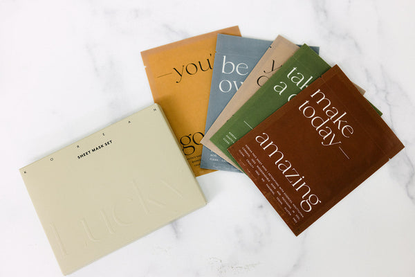 Korean Sheet Mask - You've Got This | Lucky Owl set with five colorful individual sheet mask packets arranged beside a cream-colored box on a white marble surface, promoting skincare and self-care.