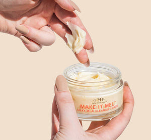 Hand holding a jar of Make it Melt Silky Milk Cleansing Balm | Farmhouse Fresh while scooping creamy balm with fingers, showcasing skincare product texture and packaging.