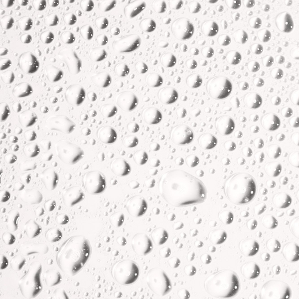Close-up of clear water droplets on a smooth surface illustrating hydration and freshness related to Face Tan Water - Dark | NUDA skincare.