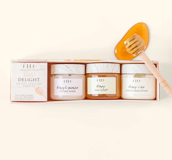 Set of three skincare jars including sea salt scrub, heel glaze, and milk lotion alongside a honey dipper with honey for the Fast Foot Revival Pedi Delight Sampler | Farmhouse Fresh.