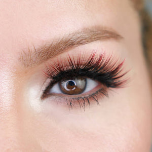Close-up of a brown eye with long, voluminous eyelashes featuring a subtle red tint, showcasing the effect of Sunny Lash - Colored | Moxielash for a vibrant look.