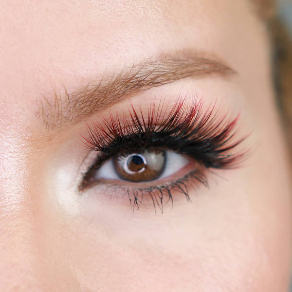 Close-up of a brown eye with long, voluminous eyelashes featuring a subtle red tint, showcasing the effect of Sunny Lash - Colored | Moxielash for a vibrant look.