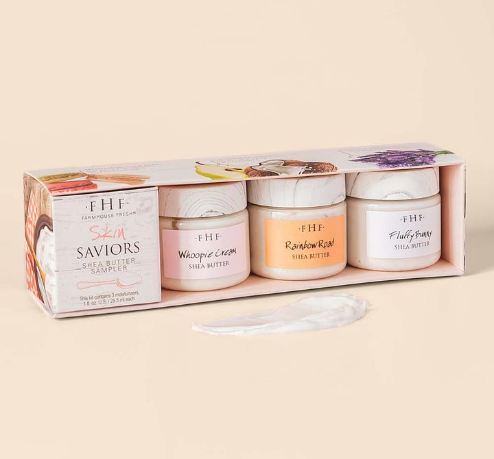 A boxed set of Skin Saviors Shea Butter Sampler | Farmhouse Fresh featuring three jars of creamy shea butter in soft pastel colors, displayed with a dollop of the product on a light background.