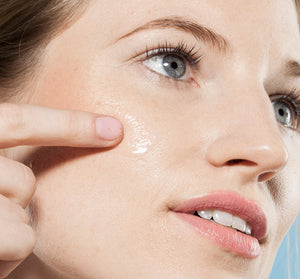 Close-up of a woman applying Eternal Light® Vitamin Enhanced Illuminating Serum | Farmhouse Fresh to her cheek, highlighting skincare and radiant skin care routine.