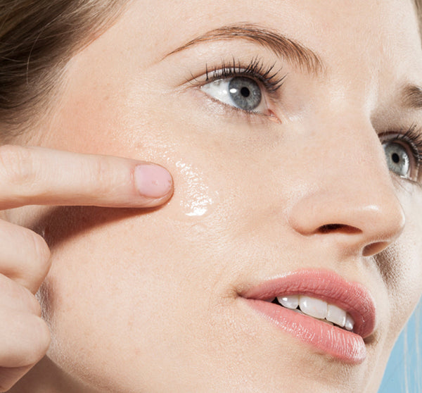 Close-up of a woman applying Eternal Light® Vitamin Enhanced Illuminating Serum | Farmhouse Fresh to her cheek, highlighting skincare and radiant skin care routine.