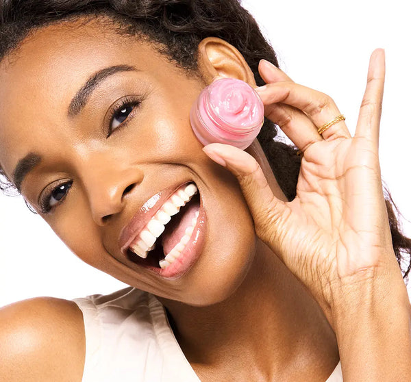 Happy woman holding a small jar of Sweet Cactus Pear Lip Drench Jelly Sleep Mask | Farmhouse Fresh near her face, showcasing the pink lip treatment with a smooth, creamy texture.