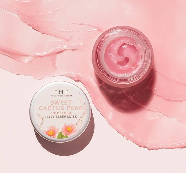 Open jar of Sweet Cactus Pear Lip Drench Jelly Sleep Mask | Farmhouse Fresh with light pink jelly texture spread on pale pink surface, showcasing smooth skincare product.