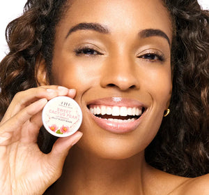 Smiling woman with glowing skin holding Sweet Cactus Pear Lip Drench Jelly Sleep Mask | Farmhouse Fresh near her face, showcasing skincare and lip care product.