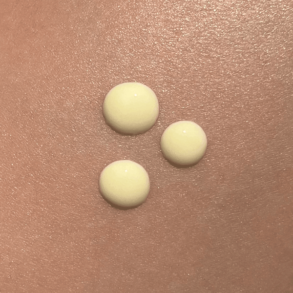 Three creamy drops of Renū Body Sculptor | Kindness Powered Skincare on smooth skin, highlighting the texture of this body care product for wellness and skin nourishment.